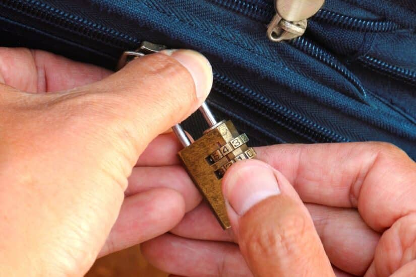 Mans Hands Trying To Open A Small Lock On A Bag