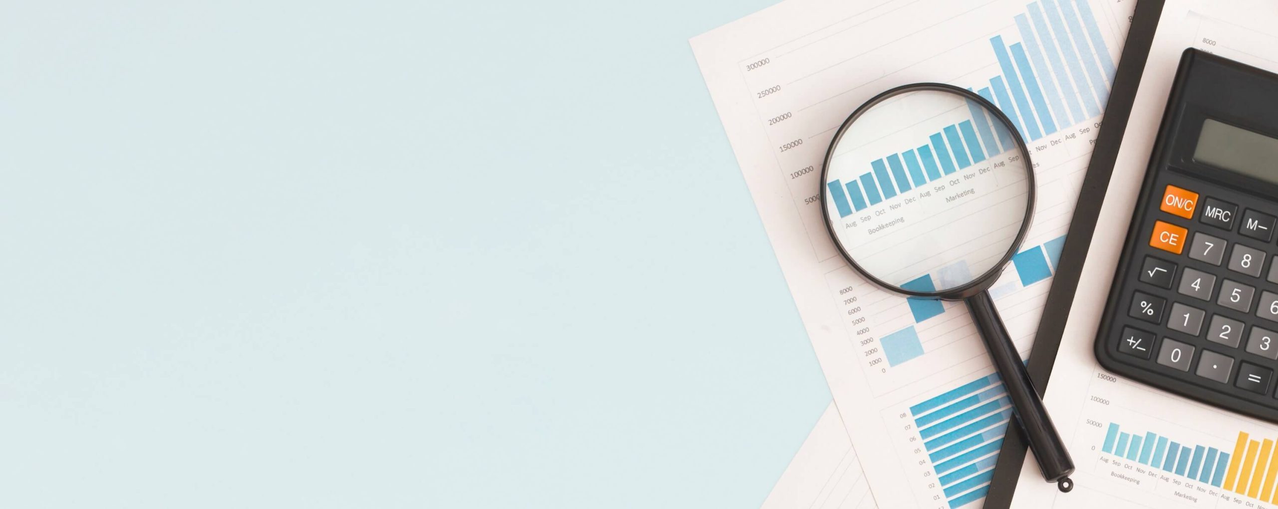 Business charts, graphs, magnifying glass and calculator on the table